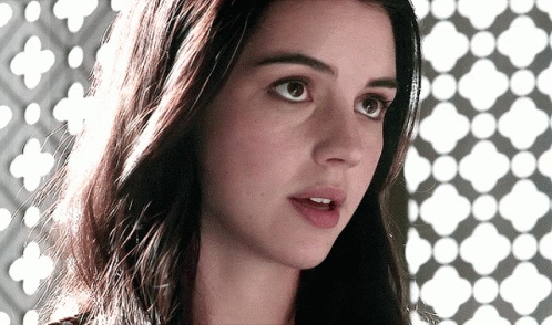 A Close Up Of A Woman 'S Face With A Geometric Pattern Behind Her GIF