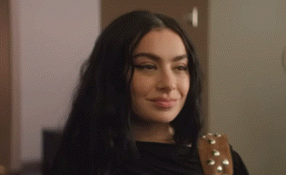 A Close Up Of A Woman 'S Face With A Guitar Strap Around Her Shoulder . GIF