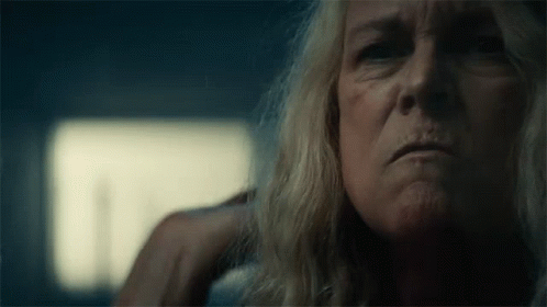 A Close Up Of A Woman 'S Face With A Hand On Her Ear In A Dark Room . GIF