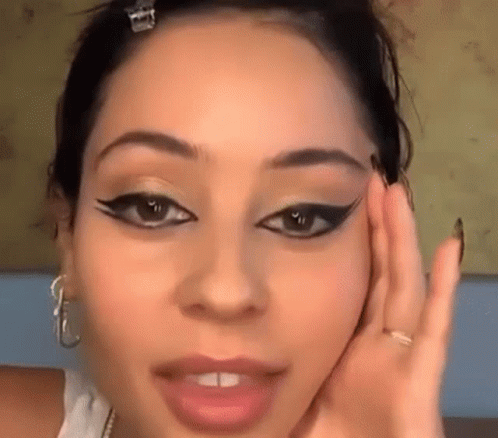 A Close Up Of A Woman 'S Face With A Hand On Her Face . GIF