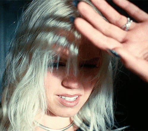 A Close Up Of A Woman 'S Face With A Hand On Her Forehead GIF