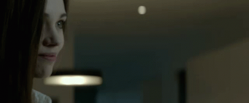 A Close Up Of A Woman 'S Face With A Light In The Background GIF