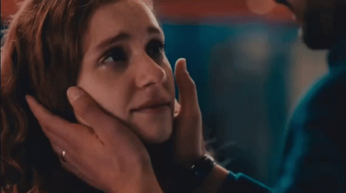 A Close Up Of A Woman 'S Face With A Man 'S Hand Touching It GIF