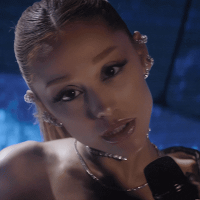 A Close Up Of A Woman 'S Face With A Microphone In Front Of Her GIF