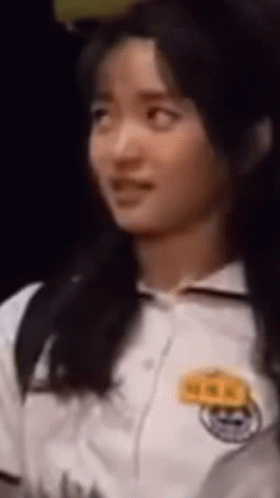 A Close Up Of A Woman 'S Face With A Name Tag On Her Chest GIF