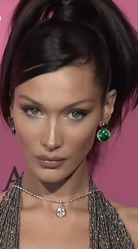 A Close Up Of A Woman 'S Face With A Necklace And Earrings GIF