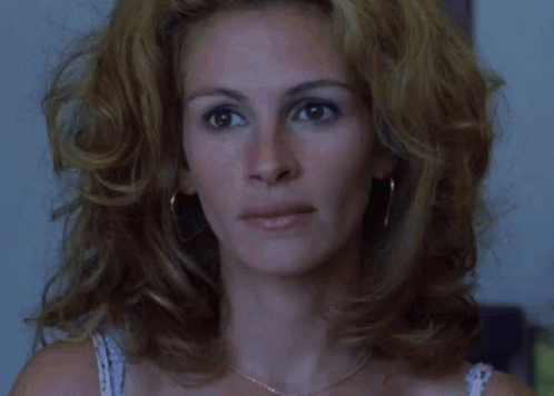 A Close Up Of A Woman 'S Face With A Necklace And Earrings GIF