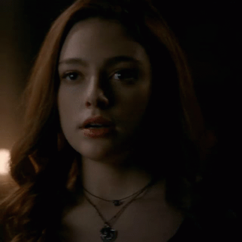 A Close Up Of A Woman 'S Face With A Necklace Around Her Neck . GIF