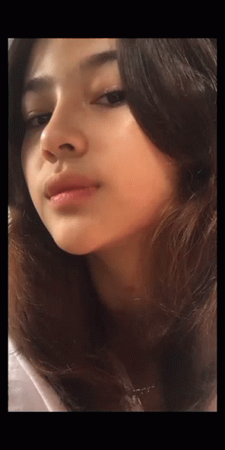 A Close Up Of A Woman 'S Face With A Necklace Around Her Neck GIF