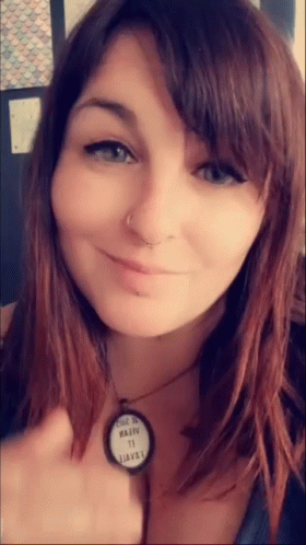 A Close Up Of A Woman 'S Face With A Necklace That Says ' Made In Usa ' On It GIF