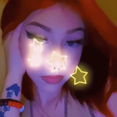 A Close Up Of A Woman 'S Face With A Neon Star On It . GIF