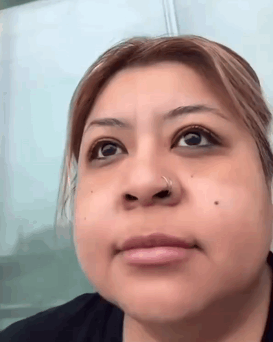 a close up of a woman 's face with a nose ring and a black shirt .