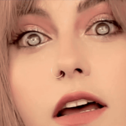 A Close Up Of A Woman 'S Face With A Nose Ring And A Surprised Look On Her Face . GIF