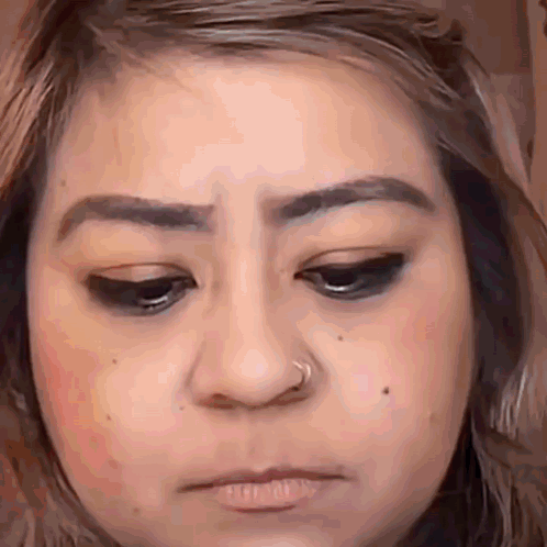 a close up of a woman 's face with a nose ring on her nose .