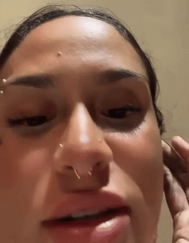 A Close Up Of A Woman 'S Face With A Piercing In Her Nose . GIF