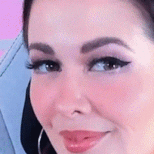 A Close Up Of A Woman 'S Face With A Pink Background And A Smile . GIF
