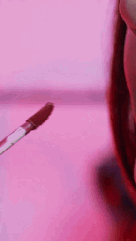 A Close Up Of A Woman 'S Face With A Pink Background And Lipstick On Her Lips . GIF