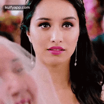 A Close Up Of A Woman 'S Face With A Pink Lip And Earrings . GIF