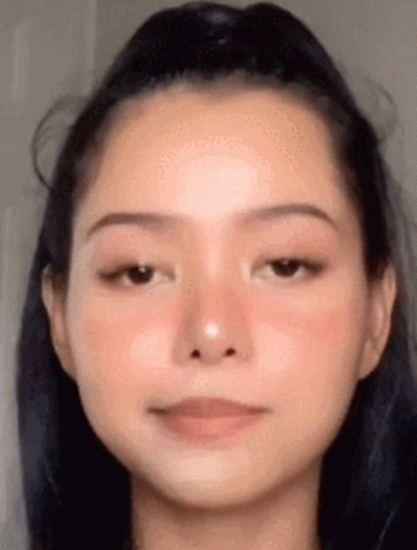 A Close Up Of A Woman 'S Face With A Ponytail And A Red Cheek . GIF