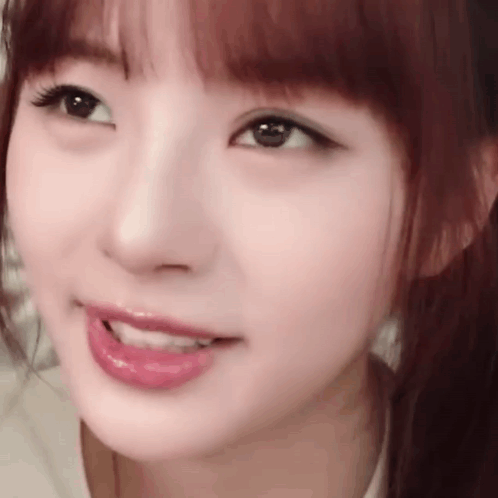 A Close Up Of A Woman 'S Face With A Ponytail And A Smile On Her Face . GIF