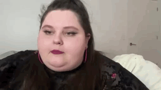 A Close Up Of A Woman 'S Face With A Ponytail And Pink Earrings . GIF