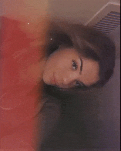 A Close Up Of A Woman 'S Face With A Red And Yellow Background GIF
