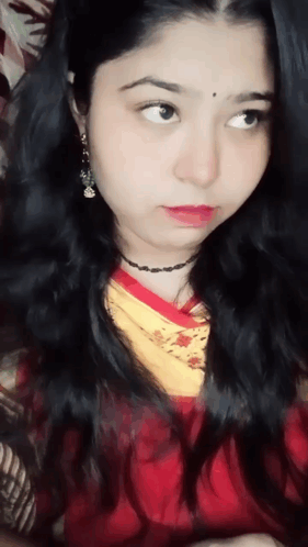 A Close Up Of A Woman 'S Face With A Red Shirt And Yellow Scarf GIF