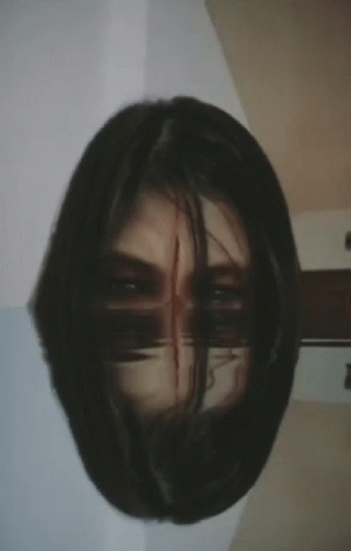A Close Up Of A Woman 'S Face With A Reflection Of Her Face In The Mirror GIF