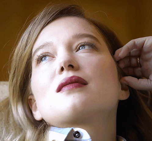 A Close Up Of A Woman 'S Face With A Ring In Her Hand GIF