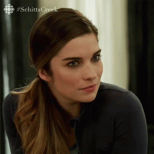 A Close Up Of A Woman 'S Face With A #Schitts Creek Logo In The Background GIF