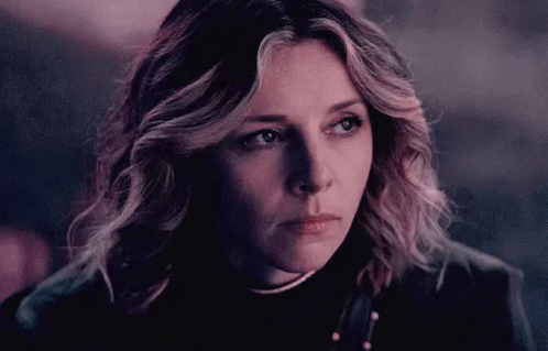 A Close Up Of A Woman 'S Face With A Serious Look On Her Face In A Dark Room . GIF
