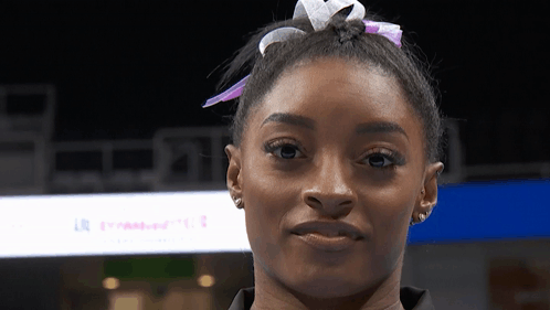 A Close Up Of A Woman 'S Face With A Sign In The Background That Says U.s. GIF
