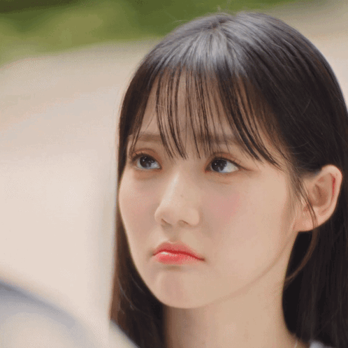 A Close Up Of A Woman 'S Face With A Slight Smirk On Her Face GIF