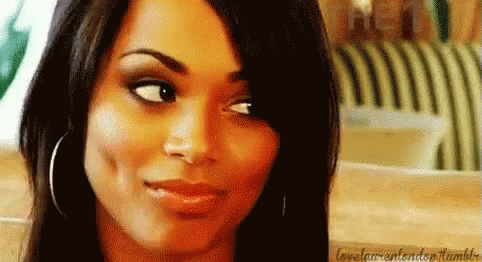 A Close Up Of A Woman 'S Face With A Smile On Her Face And A Striped Chair In The Background . GIF