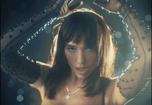 A Close Up Of A Woman 'S Face With A Star Necklace On Her Neck GIF