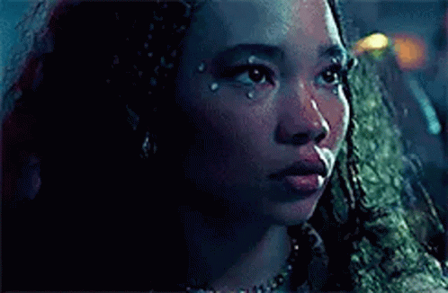 a close up of a woman 's face with a tear coming out of her eye .