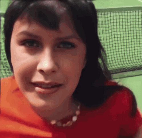A Close Up Of A Woman 'S Face With A Tennis Net Behind Her GIF
