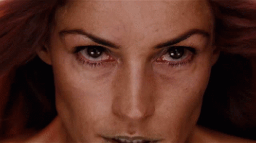 A Close Up Of A Woman 'S Face With A Very Dark Background GIF