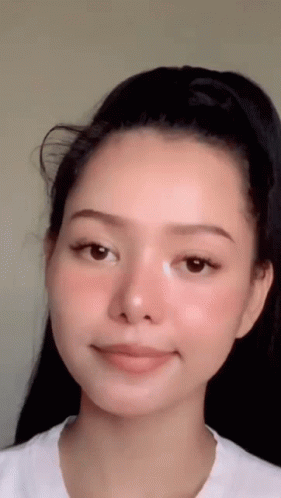 A Close Up Of A Woman 'S Face With A White Shirt On . GIF