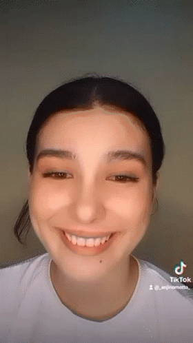 A Close Up Of A Woman 'S Face With A White Shirt On Smiling . GIF