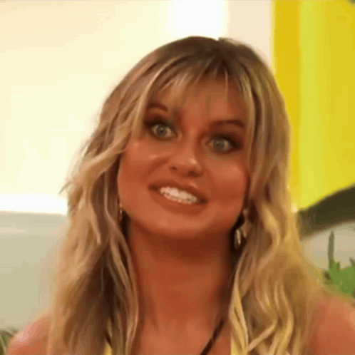 A Close Up Of A Woman 'S Face With A Yellow Background Making A Funny Face . GIF