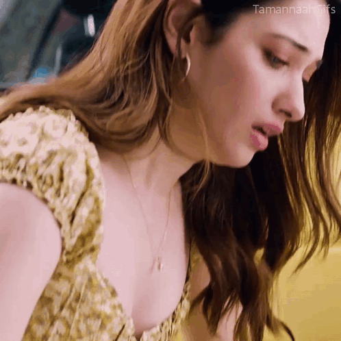 A Close Up Of A Woman 'S Face With A Yellow Background . She Is Wearing A Yellow Dress And Earrings . GIF
