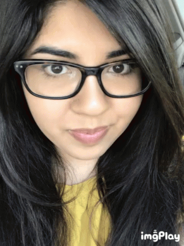 A Close Up Of A Woman 'S Face With A Yellow Shirt And Glasses GIF
