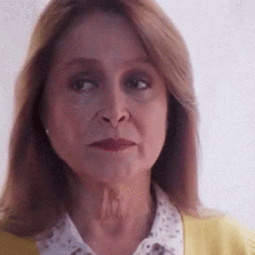 A Close Up Of A Woman 'S Face With A Yellow Sweater And A White Shirt . GIF