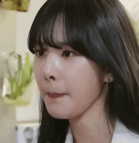 A Close Up Of A Woman 'S Face With Black Hair And Earrings . GIF