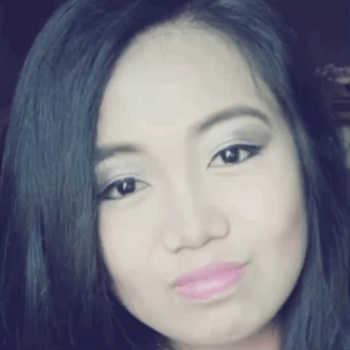 A Close Up Of A Woman 'S Face With Black Hair And Pink Lips . GIF