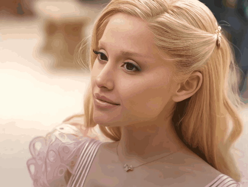 A Close Up Of A Woman 'S Face With Blonde Hair And A Necklace With A Butterfly On It GIF