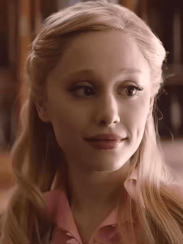 A Close Up Of A Woman 'S Face With Blonde Hair And A Pink Shirt GIF