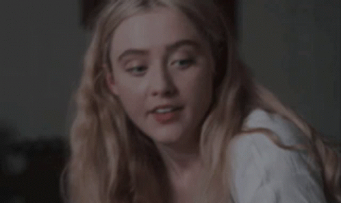 A Close Up Of A Woman 'S Face With Blonde Hair And A White Shirt . GIF