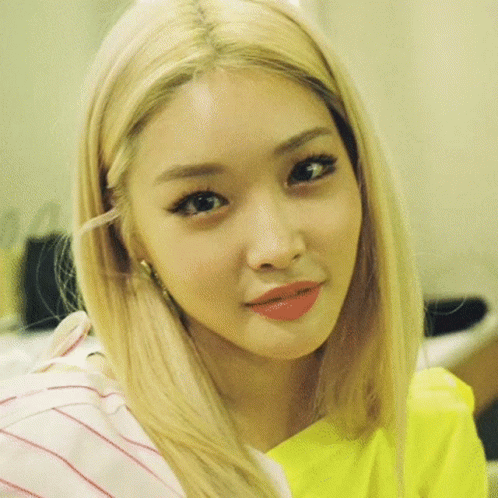 A Close Up Of A Woman 'S Face With Blonde Hair And A Yellow Shirt . GIF